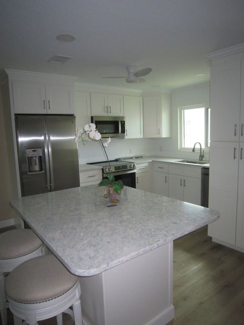 Modern kitchen under renovation with blue cabinets, unfinished island, and tools on the floor