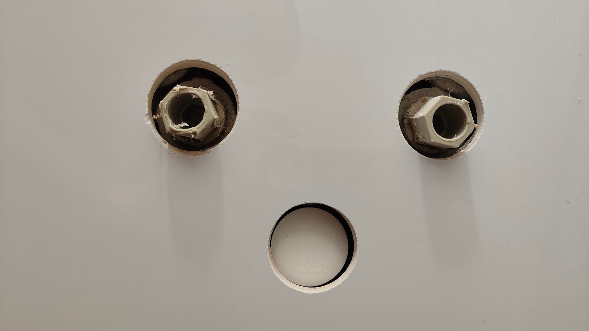 Two metal eyelets and a circular hole arranged like a simple face on a white surface Two metal eyelets and a circular hole arranged like a simple face on a white surface