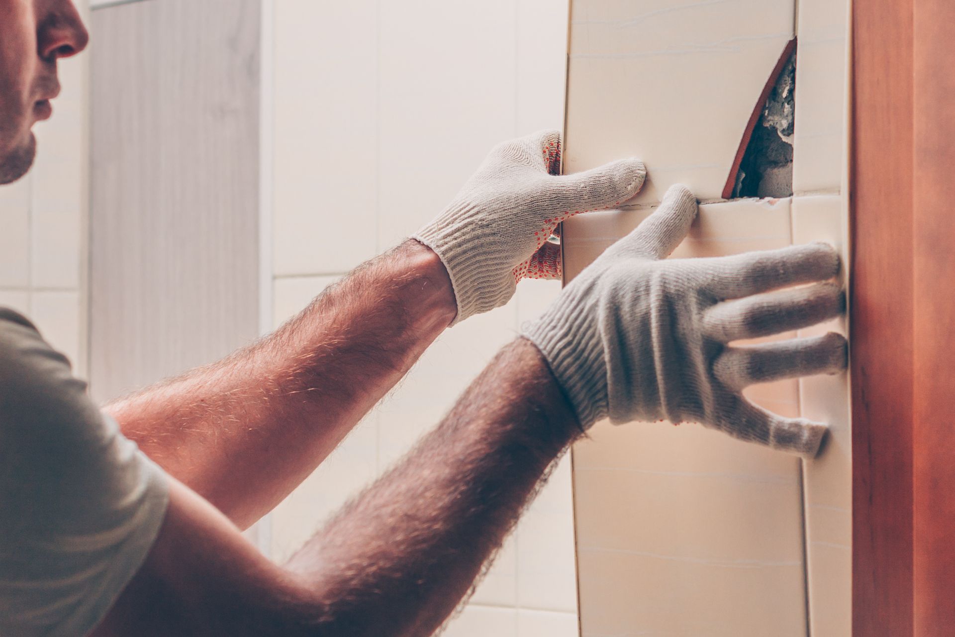 Gloved worker installing a mirror or panel on a wall indoors Gloved worker installing a mirror or panel on a wall indoors