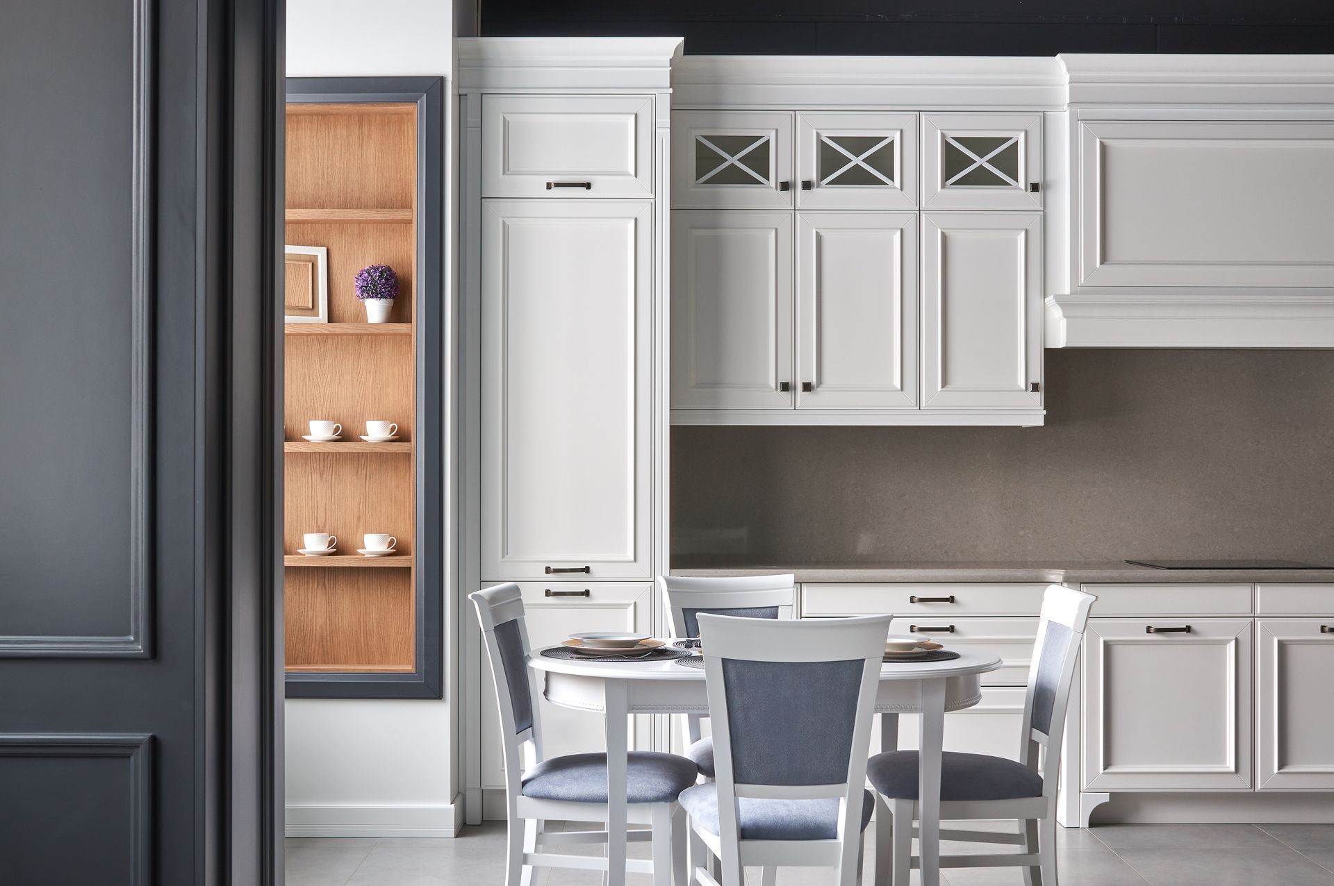 Modern white kitchen with island seating and built-in pantry, featuring gray accents and cabinets Modern white kitchen with island seating and built-in pantry, featuring gray accents and cabinets