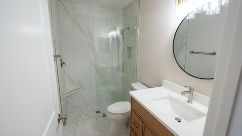 Hand connecting electrical wires to a wall outlet box beside a sink