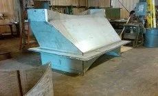 Large blue industrial metal hopper or bin in a warehouse workshop.