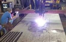 Worker using a cutting machine on large patterned sheets in a workshop, bright sparks flying
