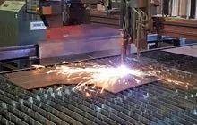 Industrial machine cutting metal with bright sparks in a workshop