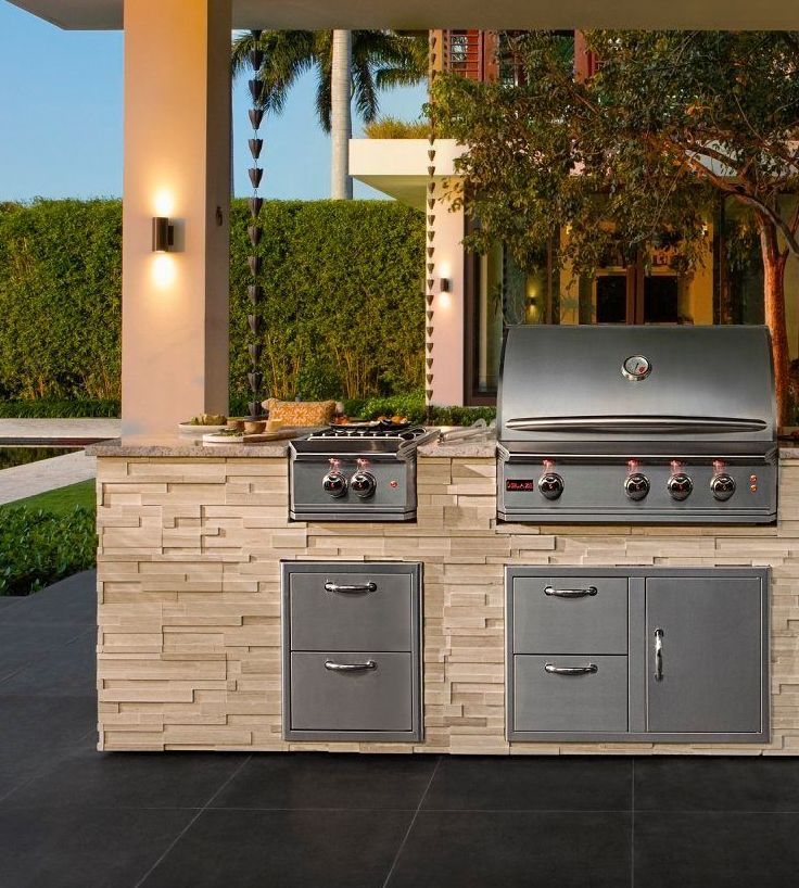 An outdoor kitchen with a grill stove and drawers