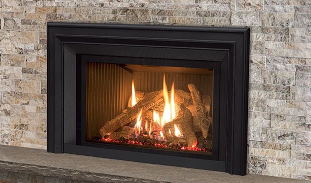 A fireplace with a lot of logs in it and a brick wall behind it.