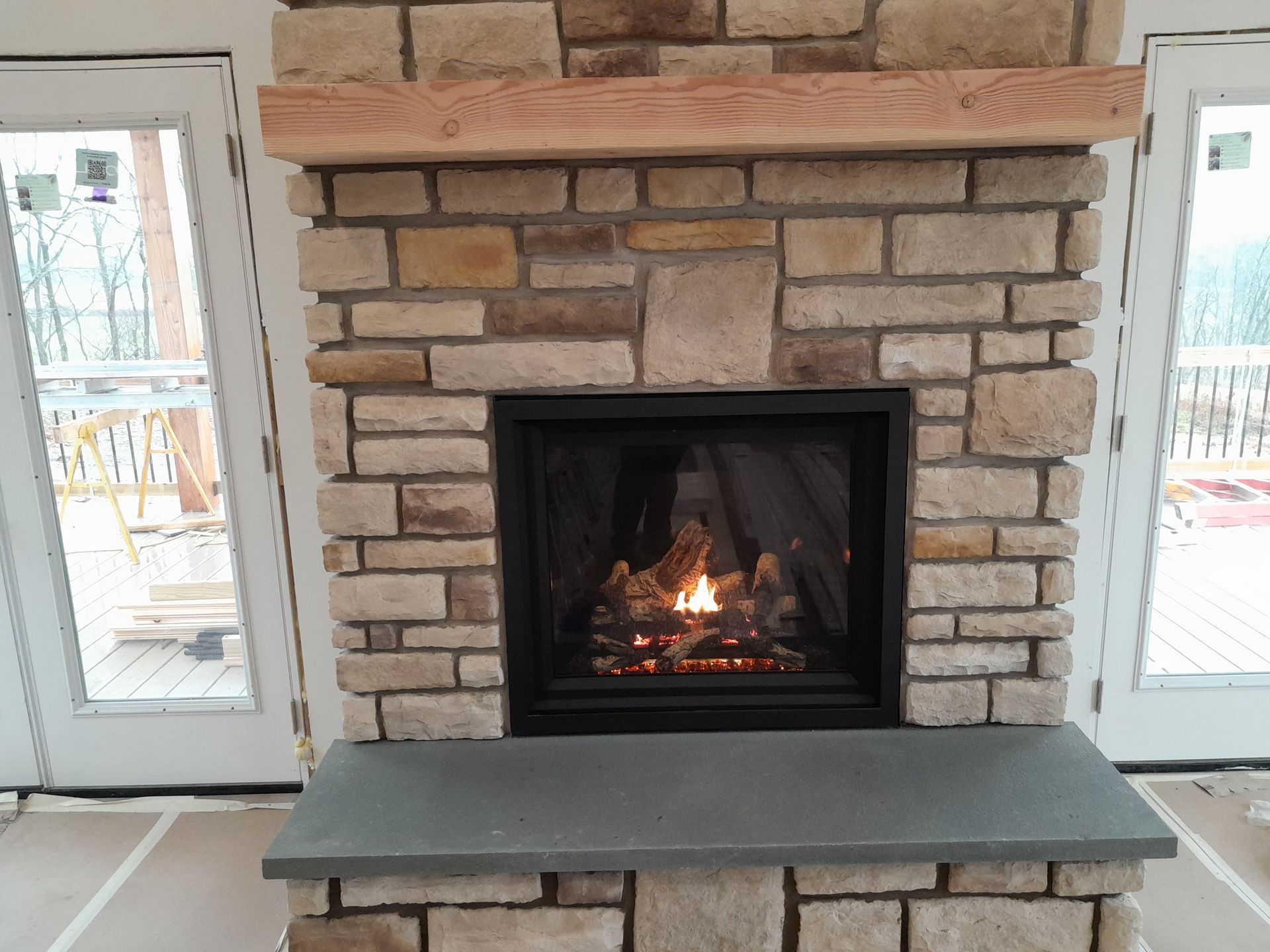 A fireplace in a living room with a brick wall and a wooden mantle.