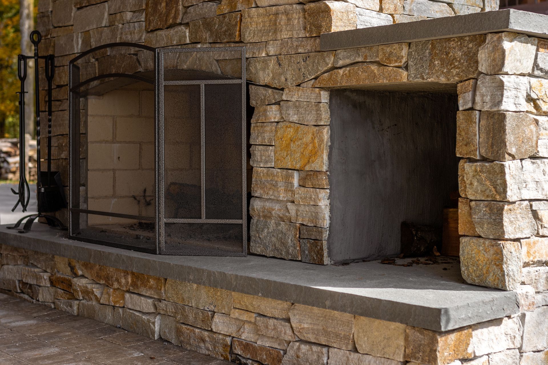 A stone fireplace with a screen on the side of it.
