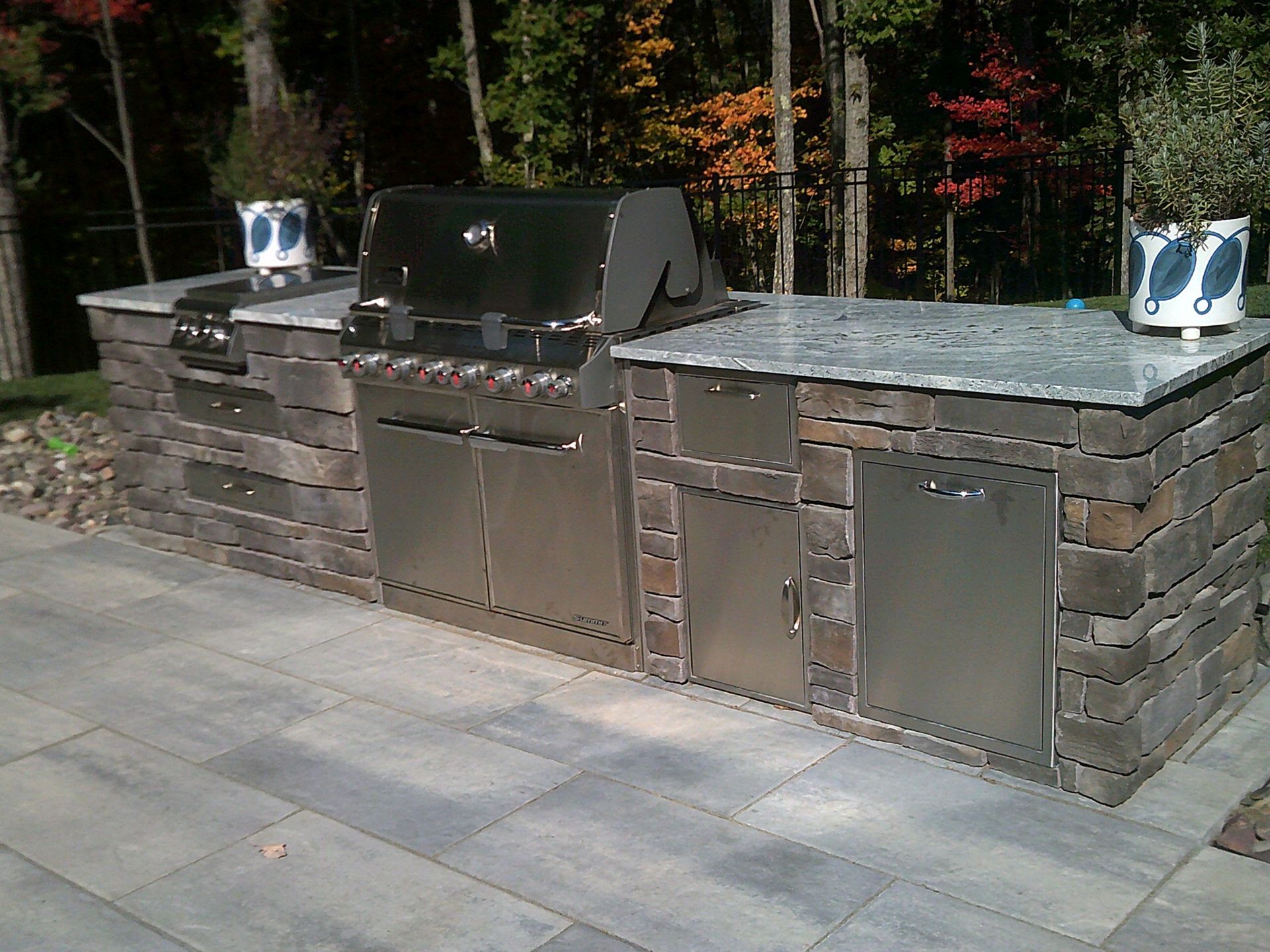 An outdoor kitchen with a stainless steel grill and a granite counter top