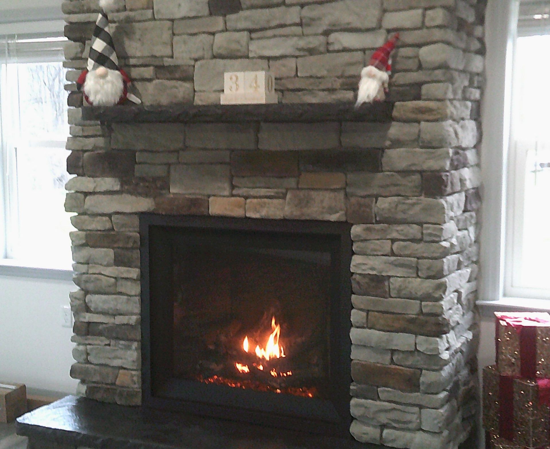 A stone fireplace with two gnomes on the mantle