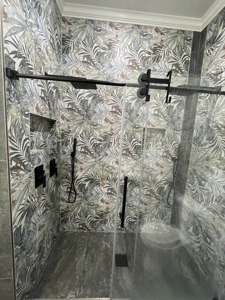 Black-and-white tiled shower with glass enclosure, rainfall showerhead, and wall-mounted fixtures