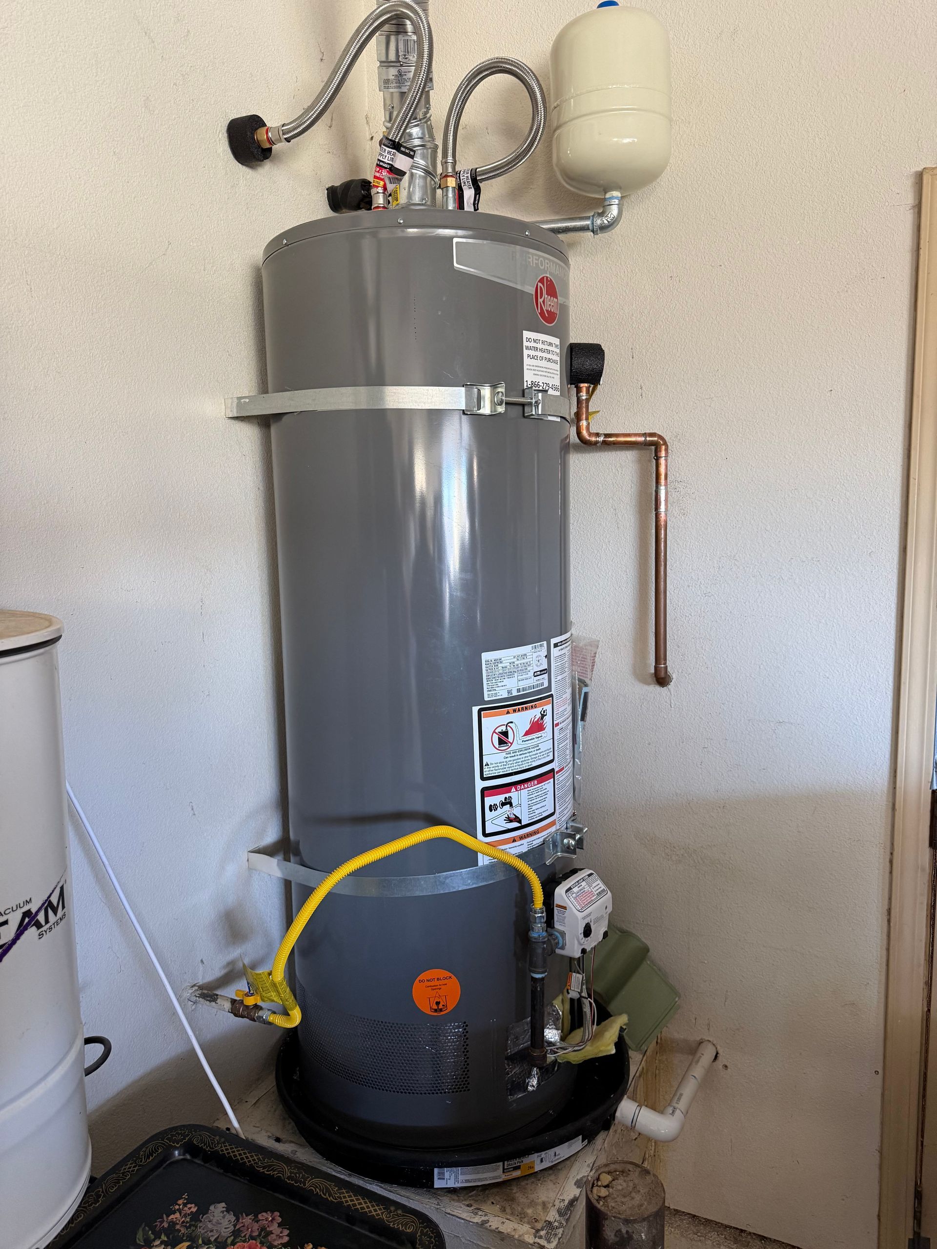 Gray water heater with pipes and expansion tank in a utility room.