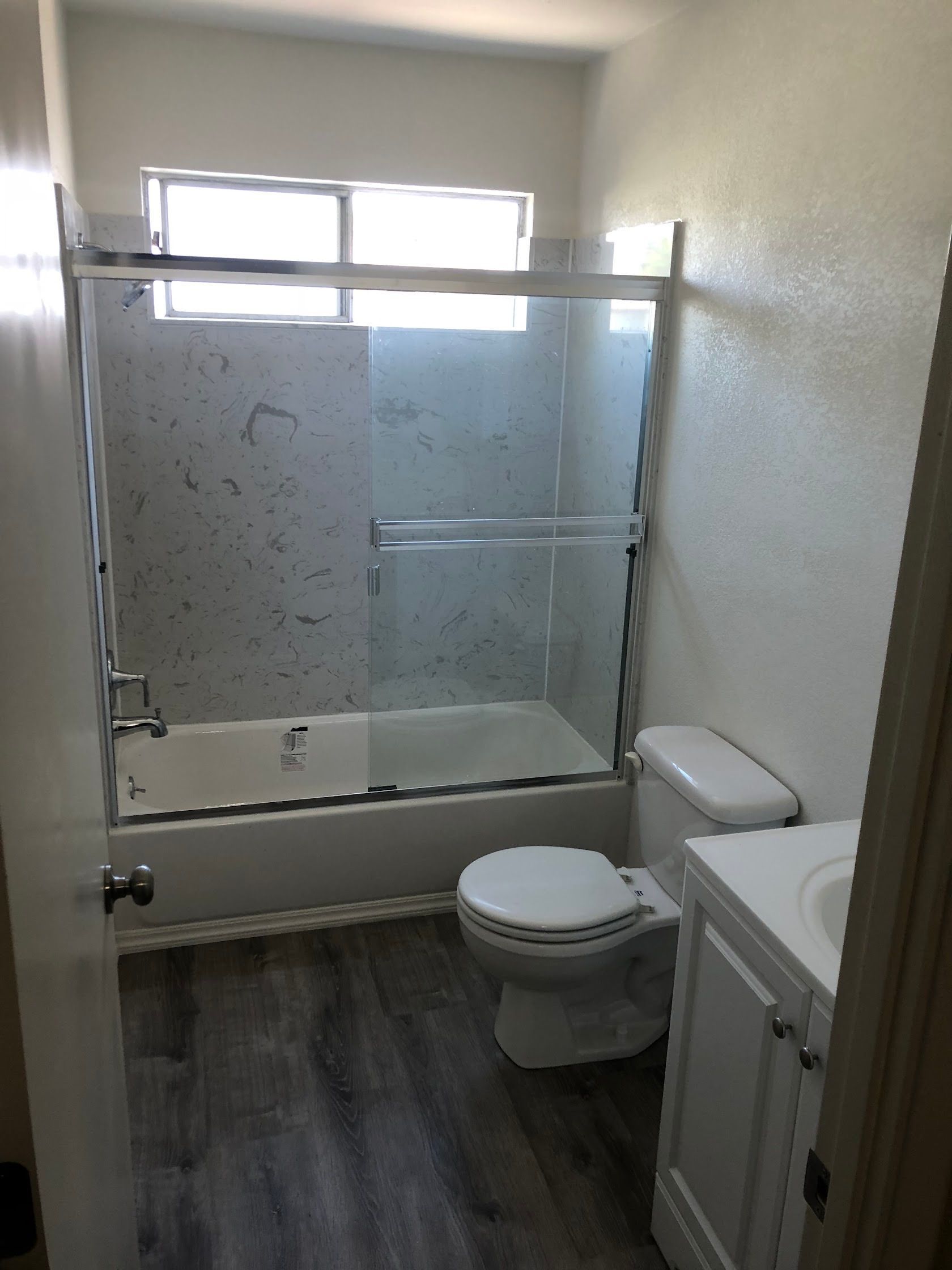Small bathroom with a bathtub, shower curtain, toilet, and vanity in light gray tones.