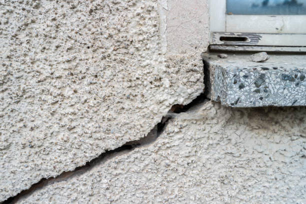 Crack in stucco wall next to a window ledge.