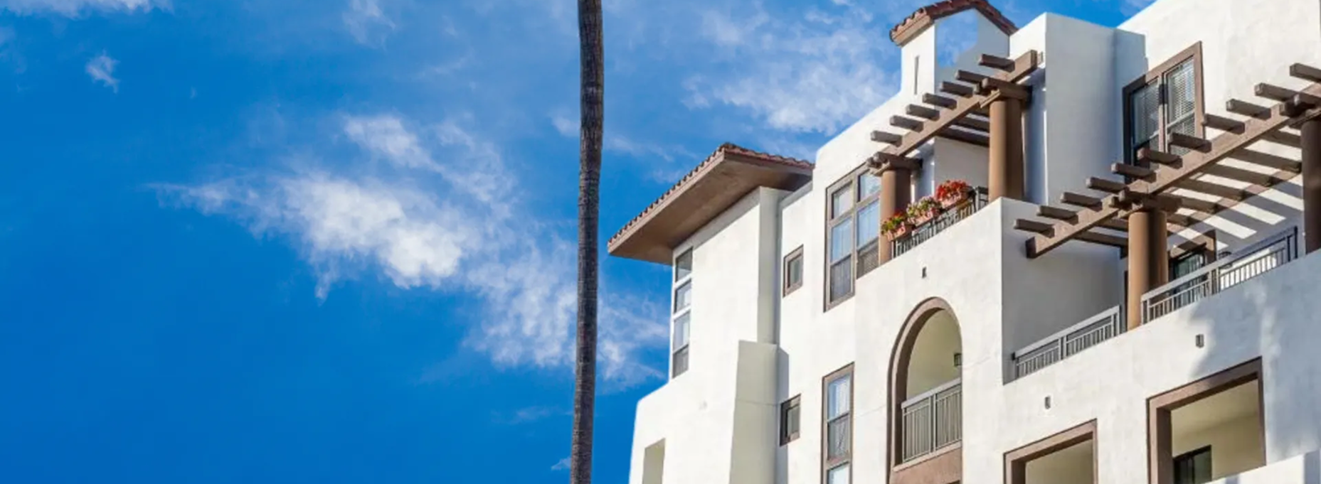 A white apartment building with a blue sky in the background.