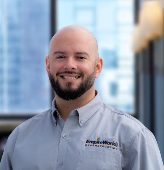 A bald man with a beard is wearing a blue suit