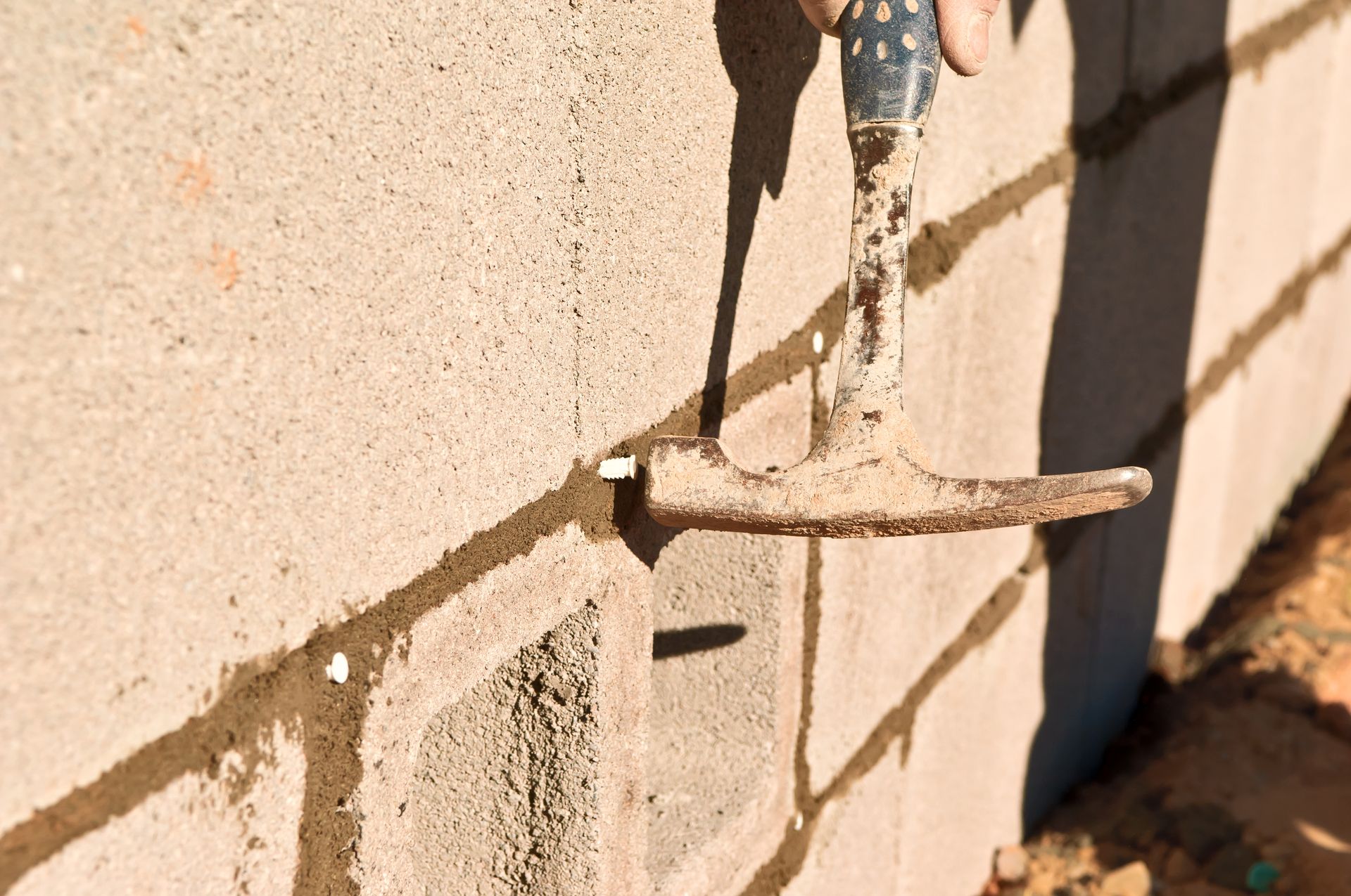Outdoor faucet with a corroded handle and water dripping down a brick wall