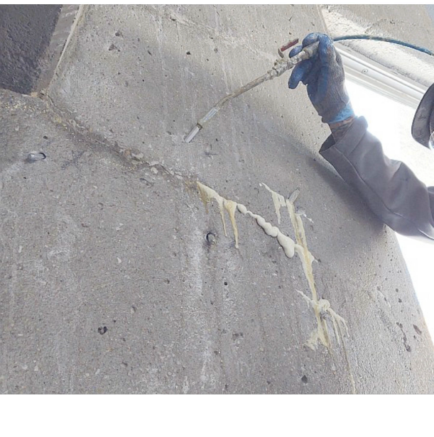 Person injecting sealant into a crack in a concrete wall.