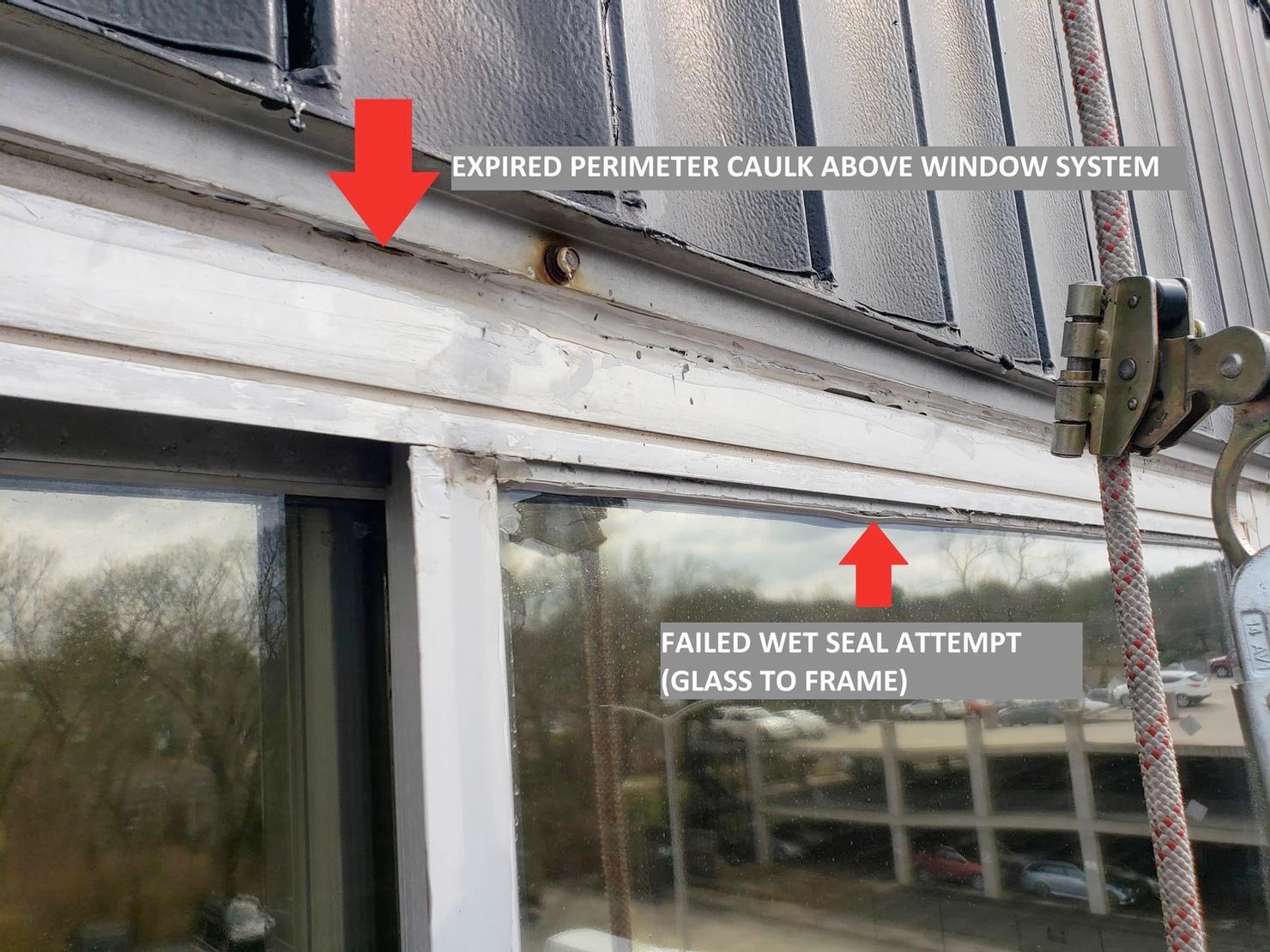 Close-up of a building exterior showing expired caulk and a failed wet seal attempt around a window system. A safety rope is visible.
