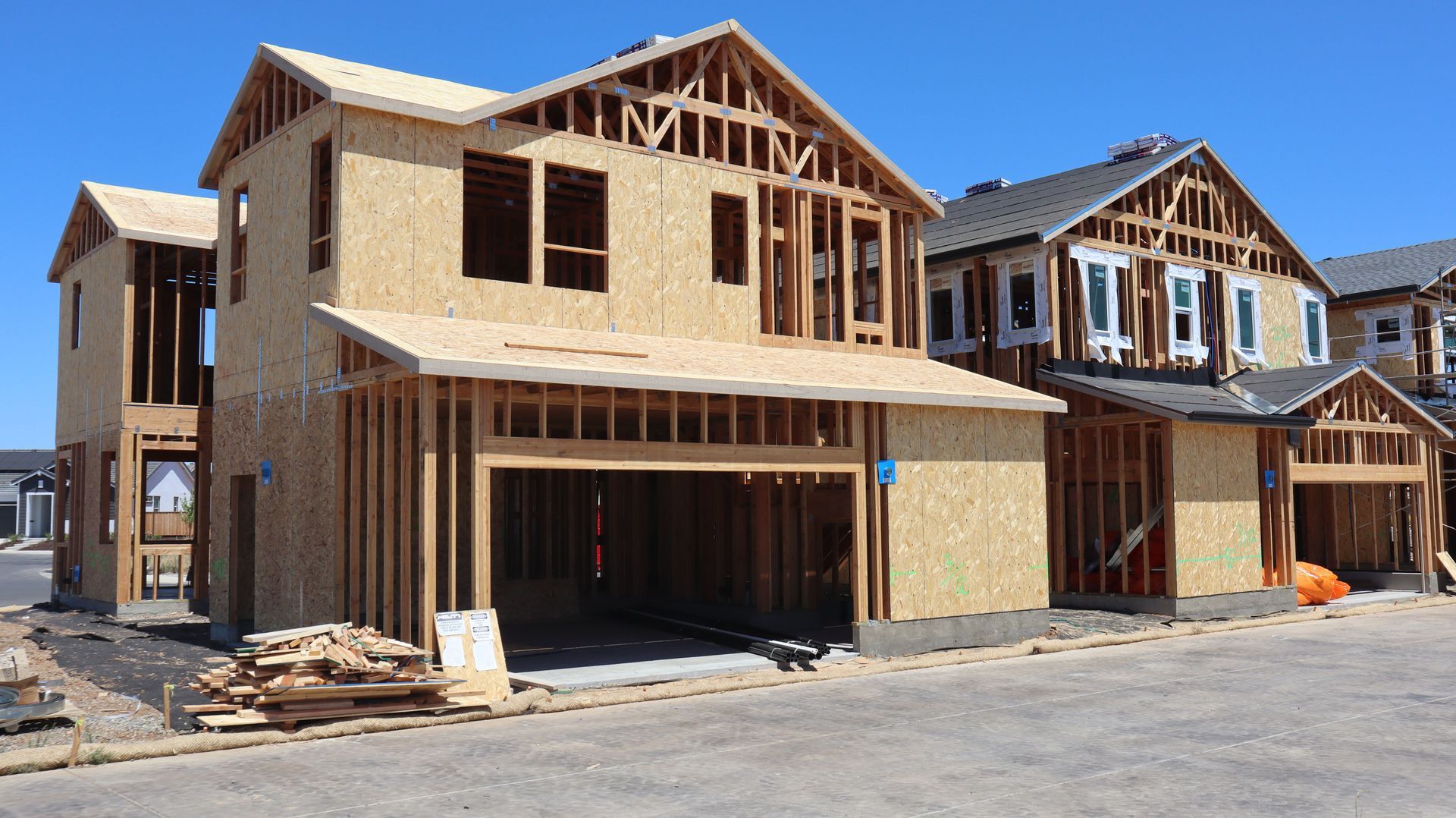 Row of unfinished wooden houses under construction on a suburban street