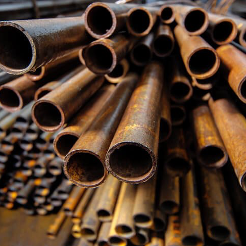 Pile of rusty metal pipes with visible circular openings.