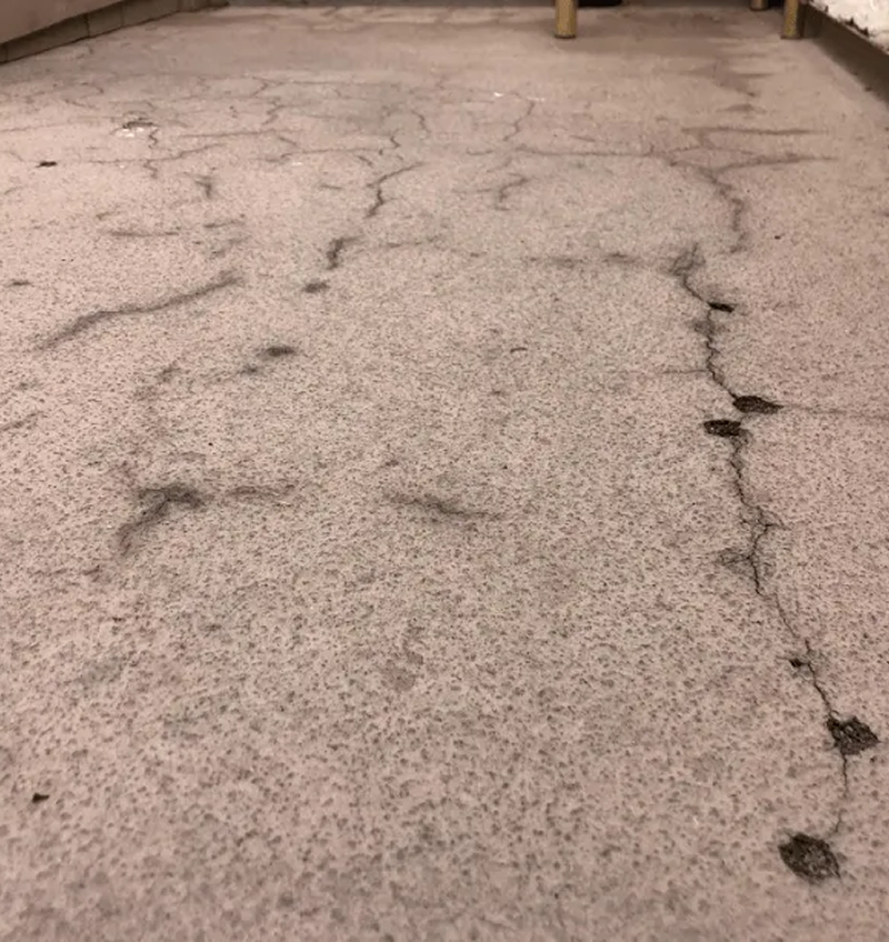 A close up of a cracked carpet in a room.