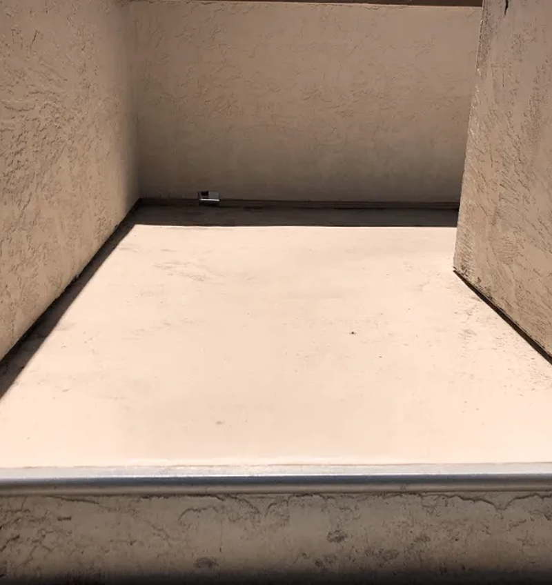 A concrete floor with stairs leading up to it in a corner of a building.