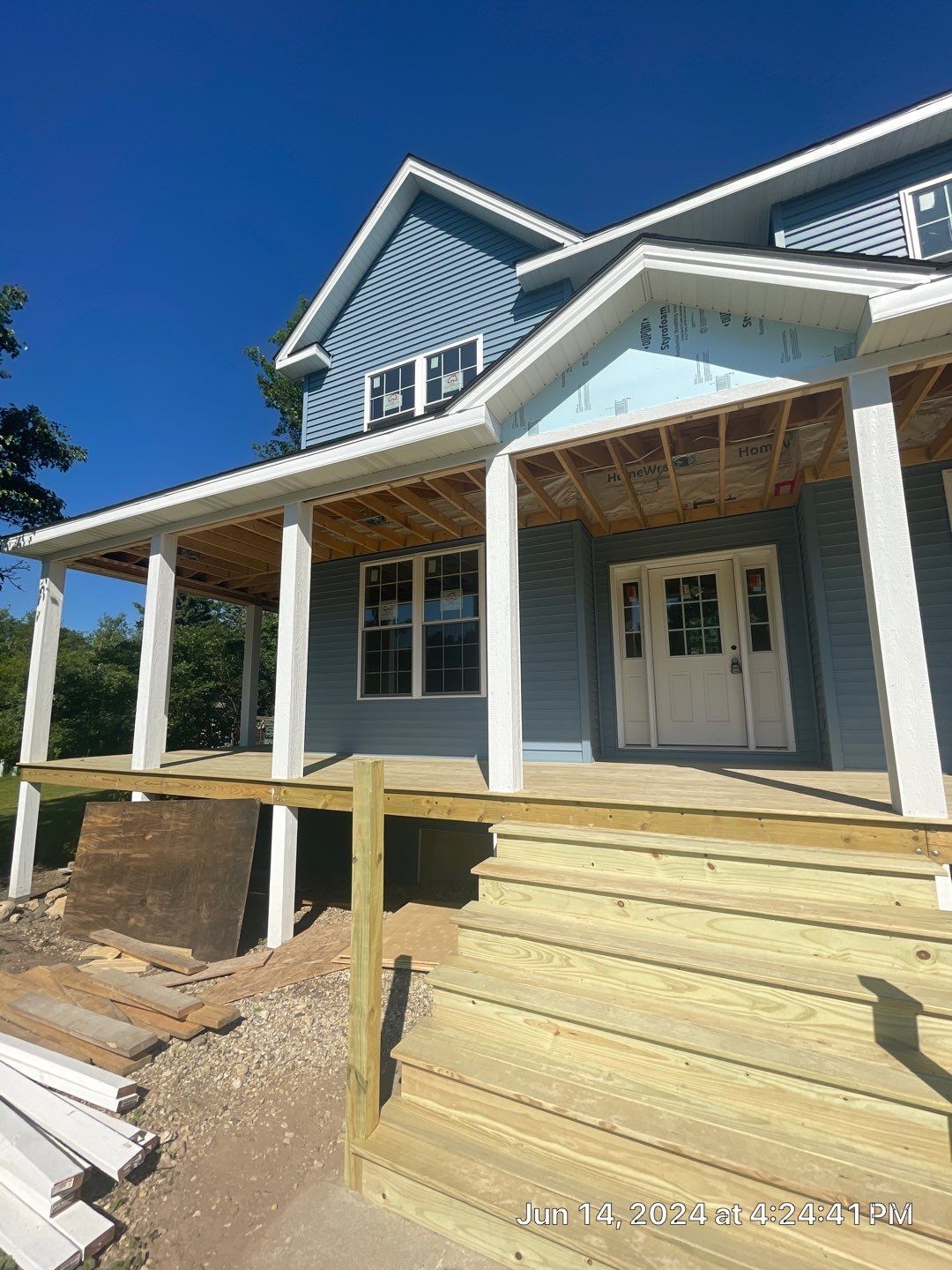 A house under construction with a large porch and stairs.