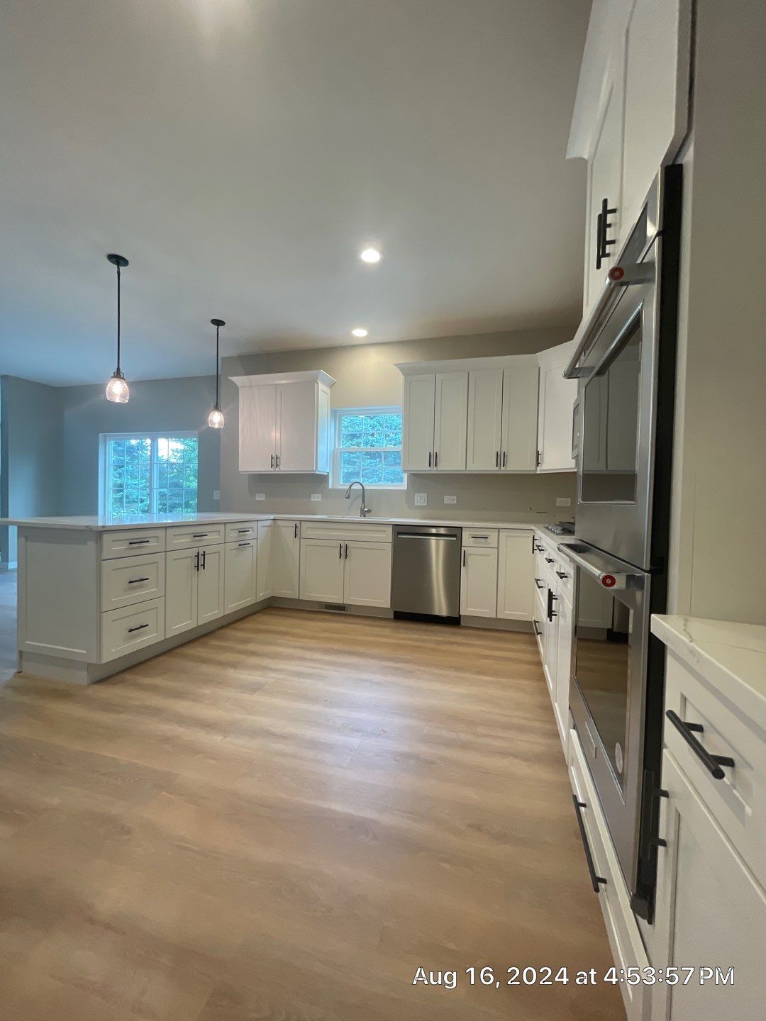 Bright, modern kitchen with white cabinets, stainless steel appliances, and light wood floors.