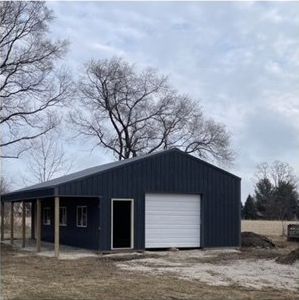 A black garage with a white garage door and a porch.