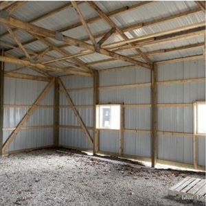 The inside of a building with wooden beams and a metal roof.
