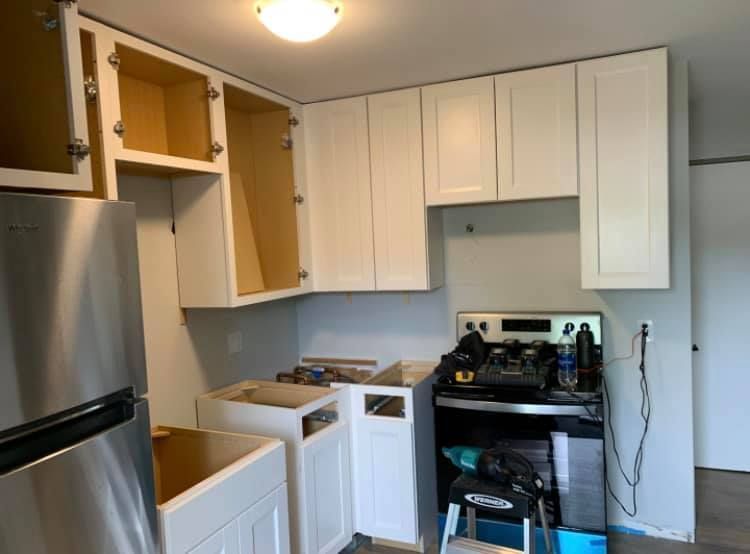 A kitchen with white cabinets and a stainless steel refrigerator.