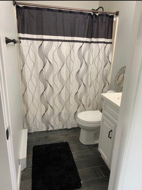 A bathroom with a toilet , sink and shower curtain