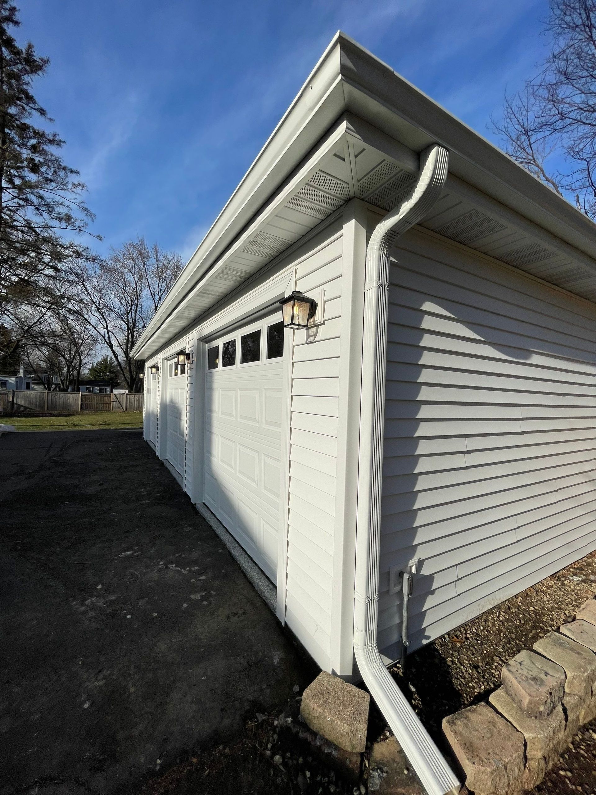 A white garage with a gutter on the side of it