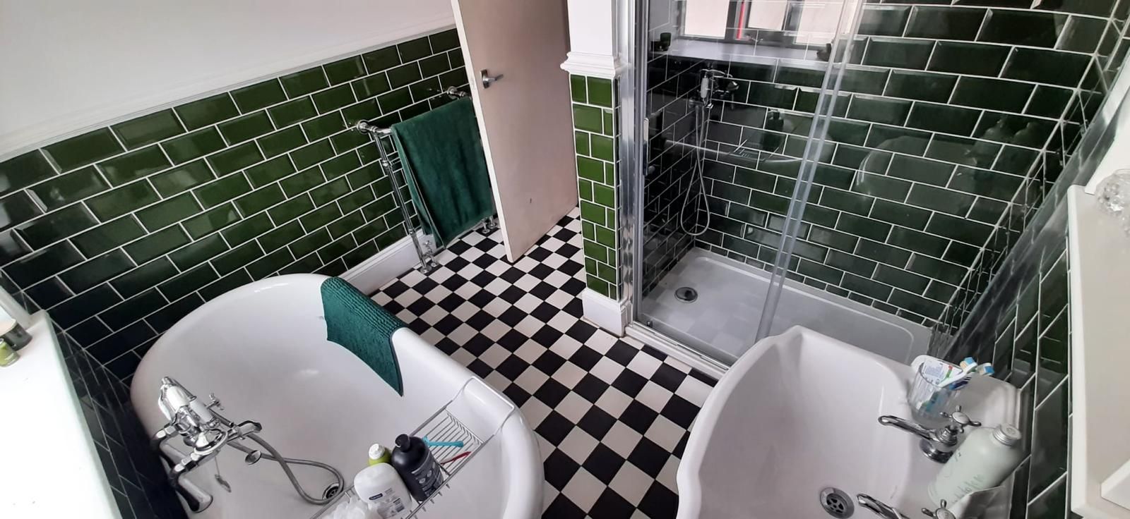 A bathroom with green tiles and a black and white checkered floor.