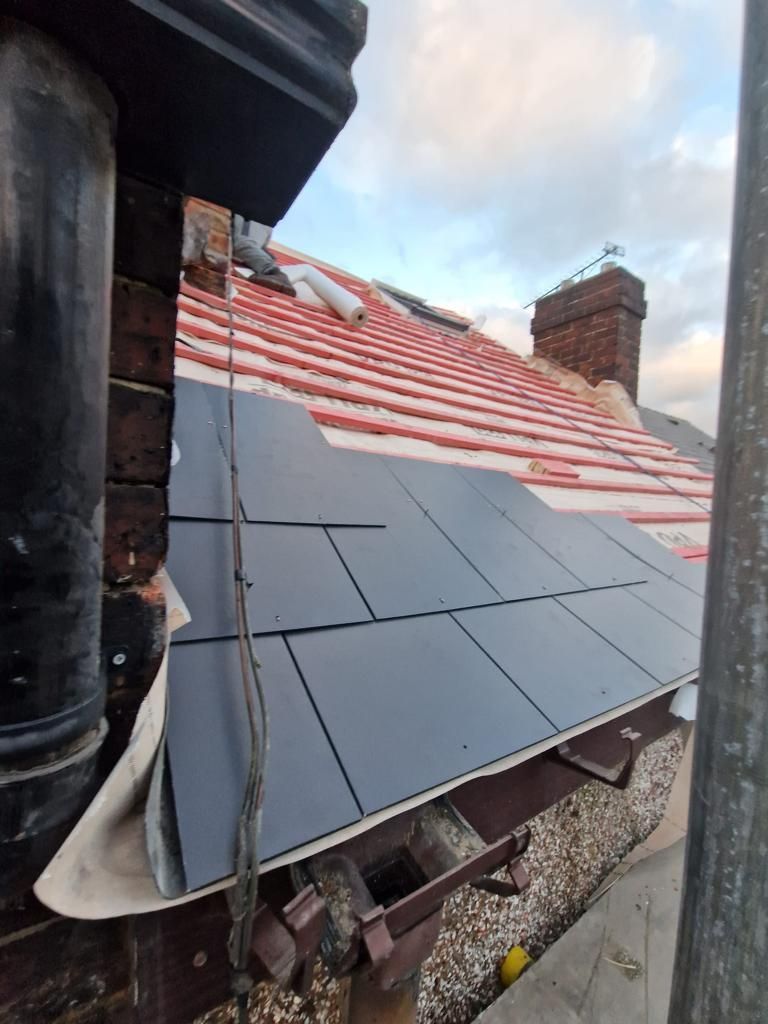 A close up of a roof with a chimney in the background.