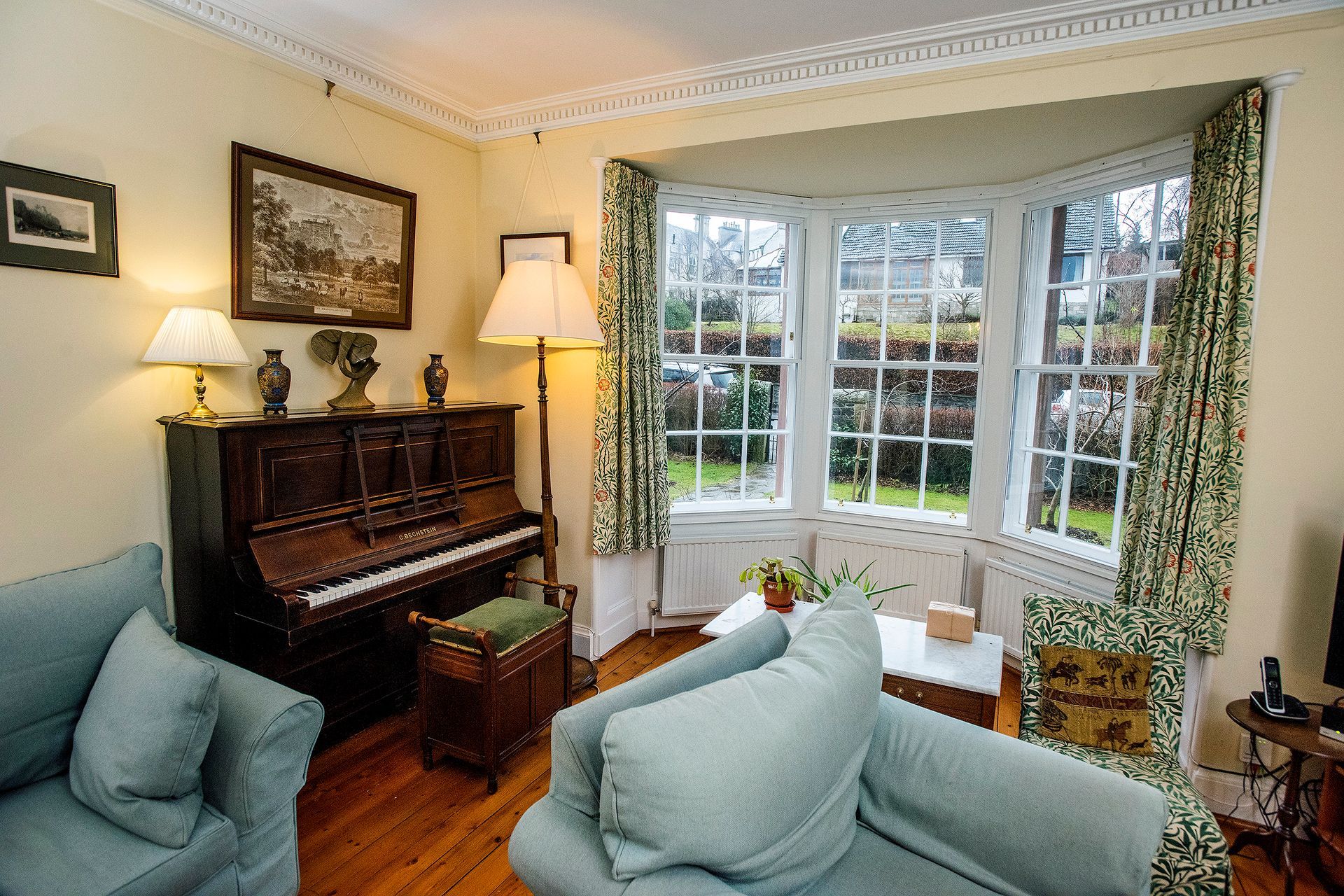 A living room with a piano and a lot of windows