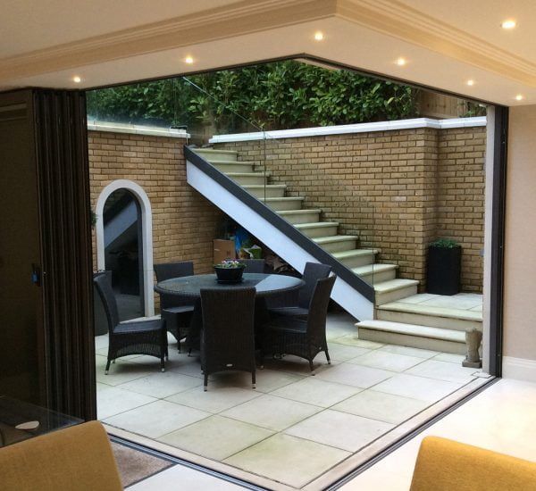 A patio with a table and chairs and stairs in the background