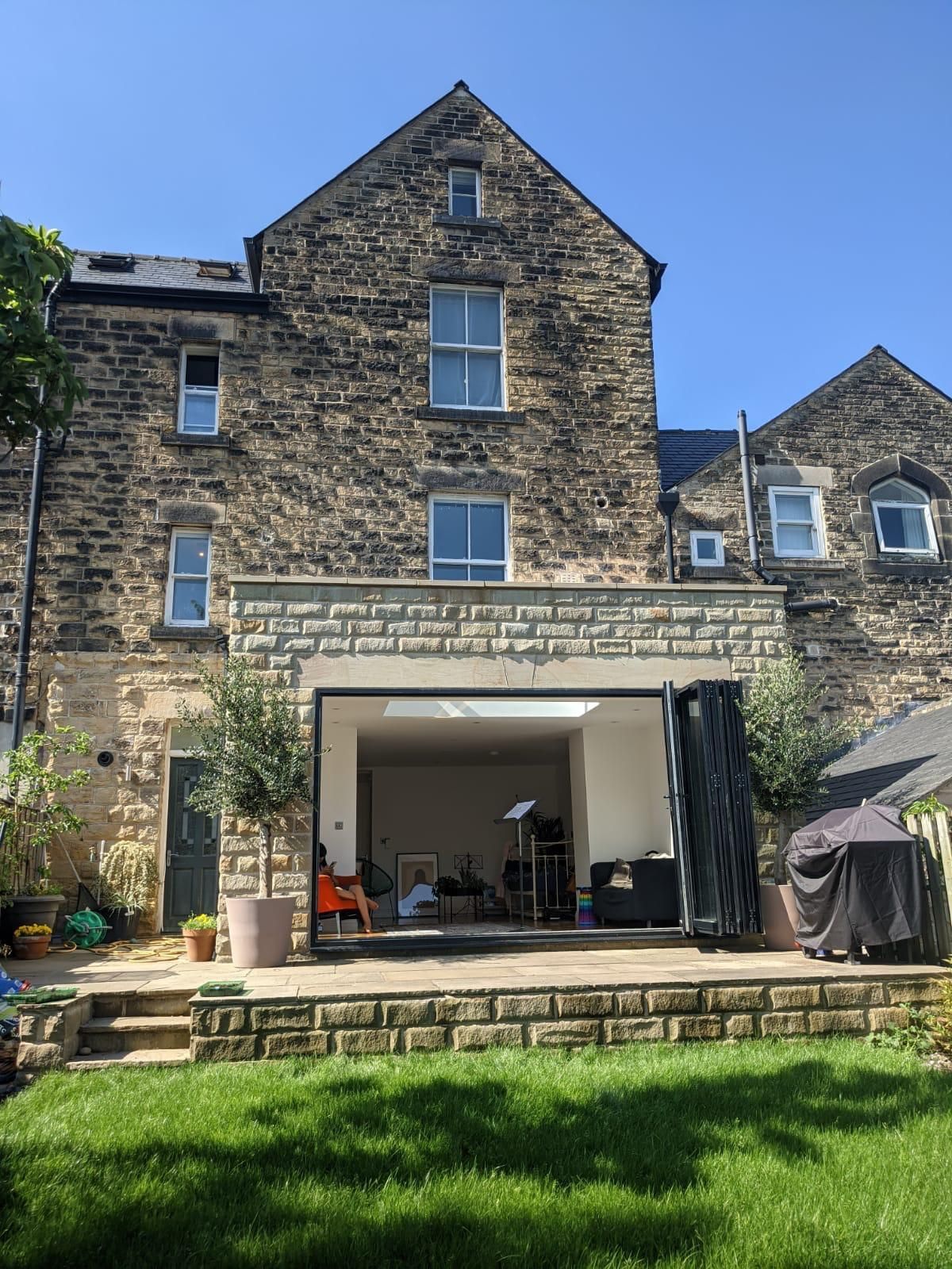 The back of a large stone house with a large sliding glass door.