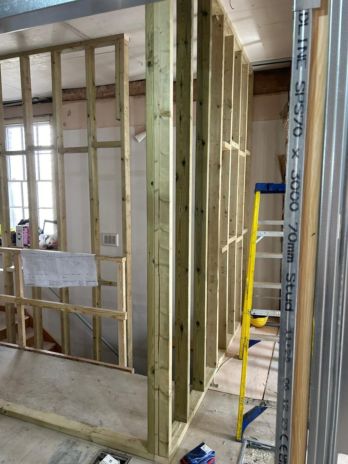 A room is being built with wooden walls and a yellow ladder.