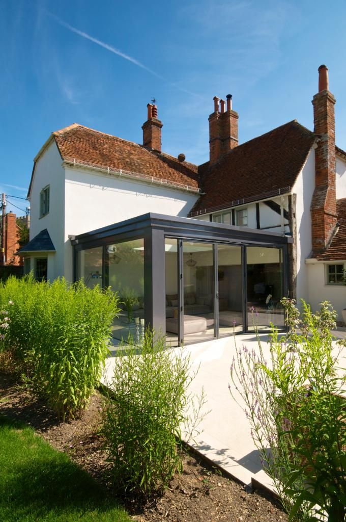 A white house with a large glass extension on the side of it.