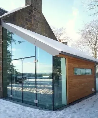 A house with a lot of windows and snow on the ground