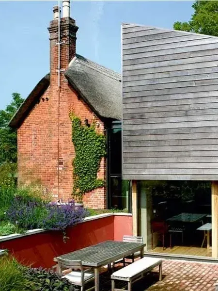 A brick building with a chimney and a table and benches in front of it