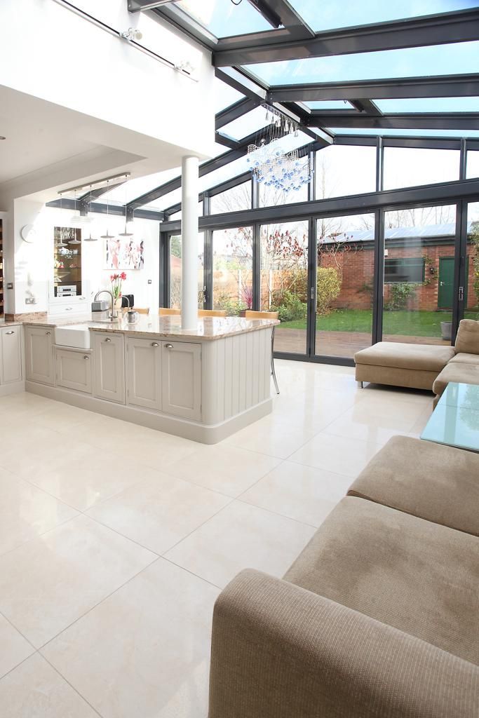 A living room with a couch and a kitchen with a lot of windows.