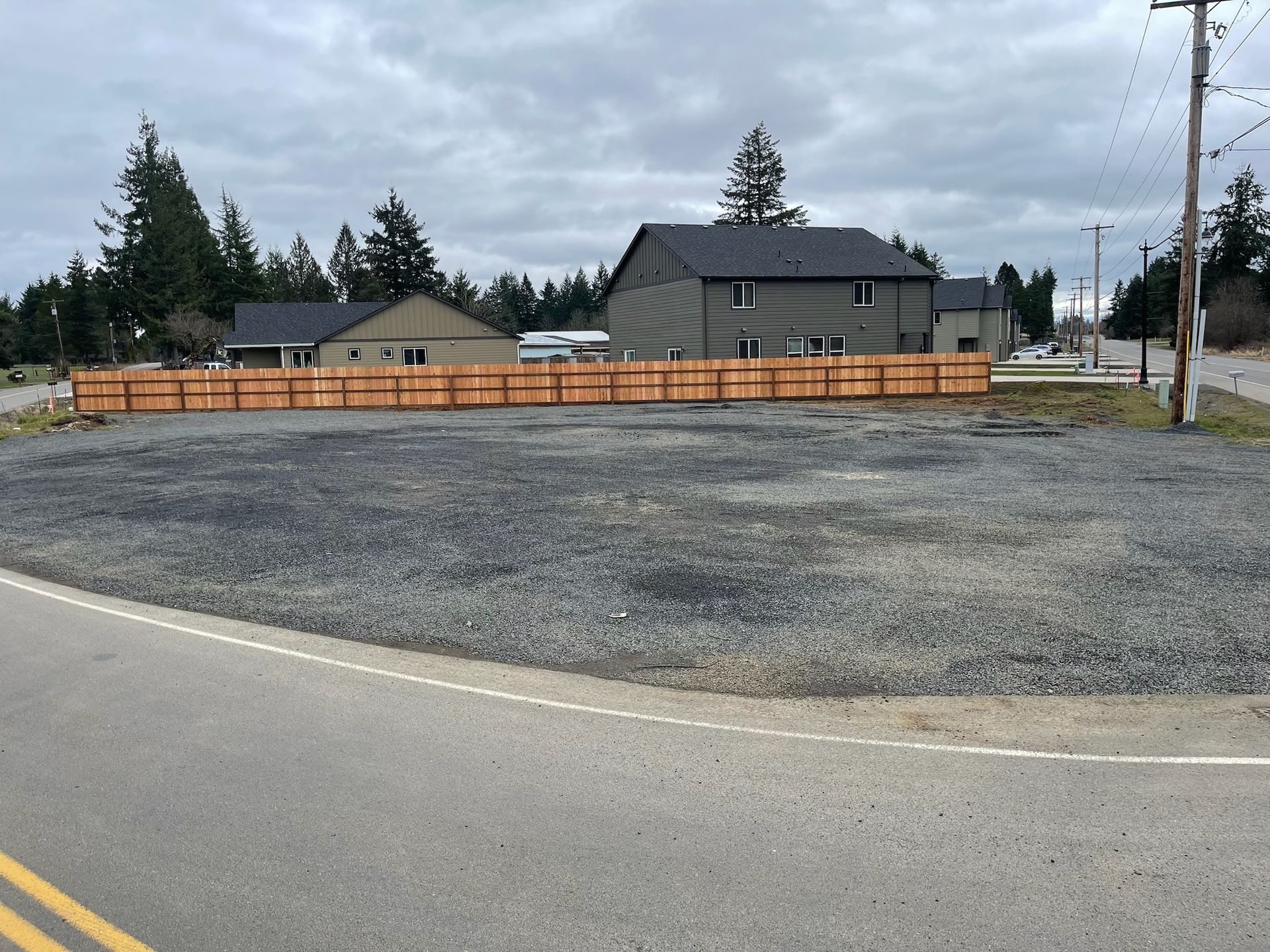 A house is behind a wooden fence on the side of the road
