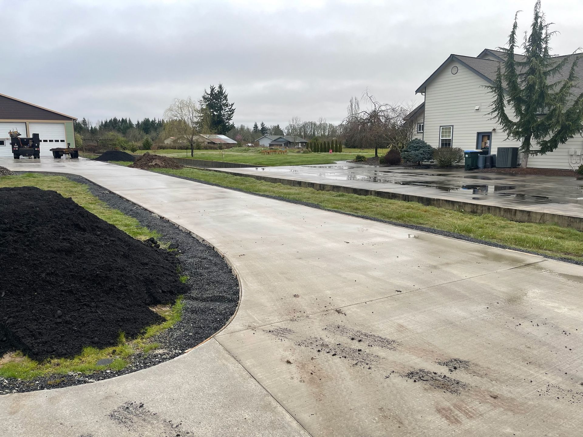 A concrete driveway leading to a house on a cloudy day