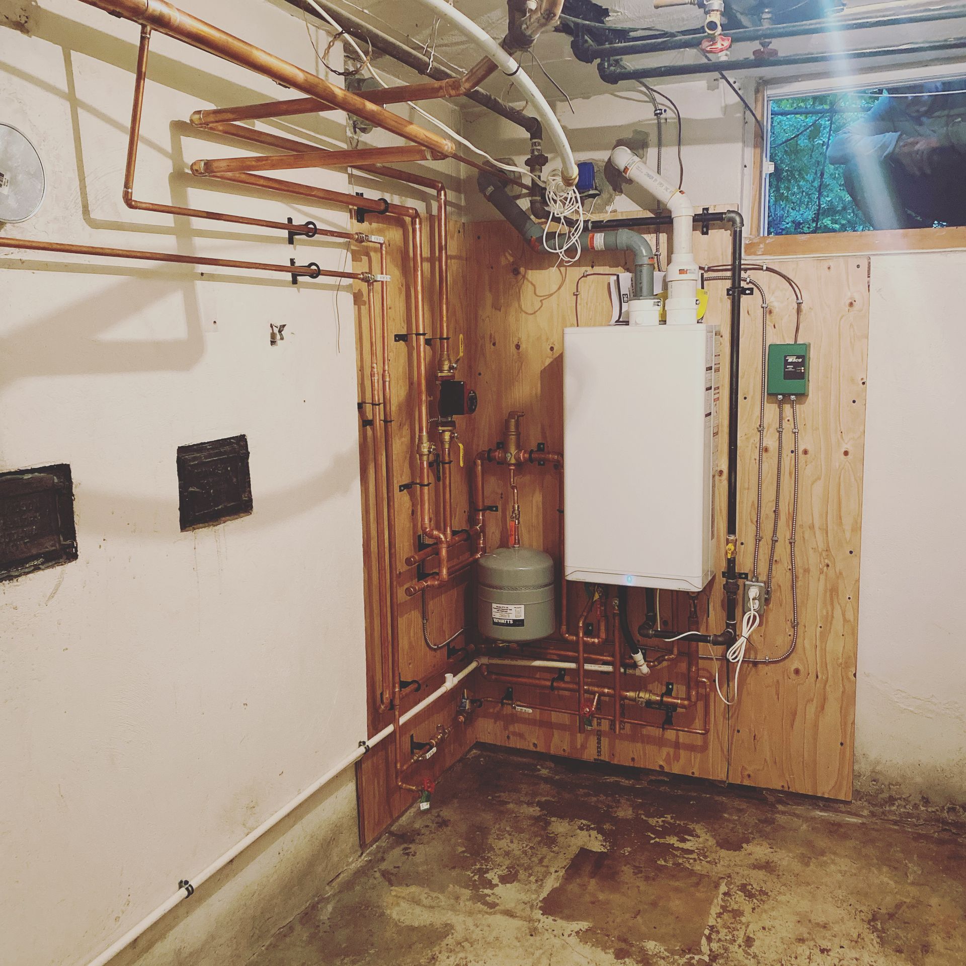 A room with a boiler and pipes on the wall