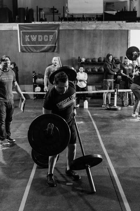 A black and white photo of a man lifting a barbell in a gym.