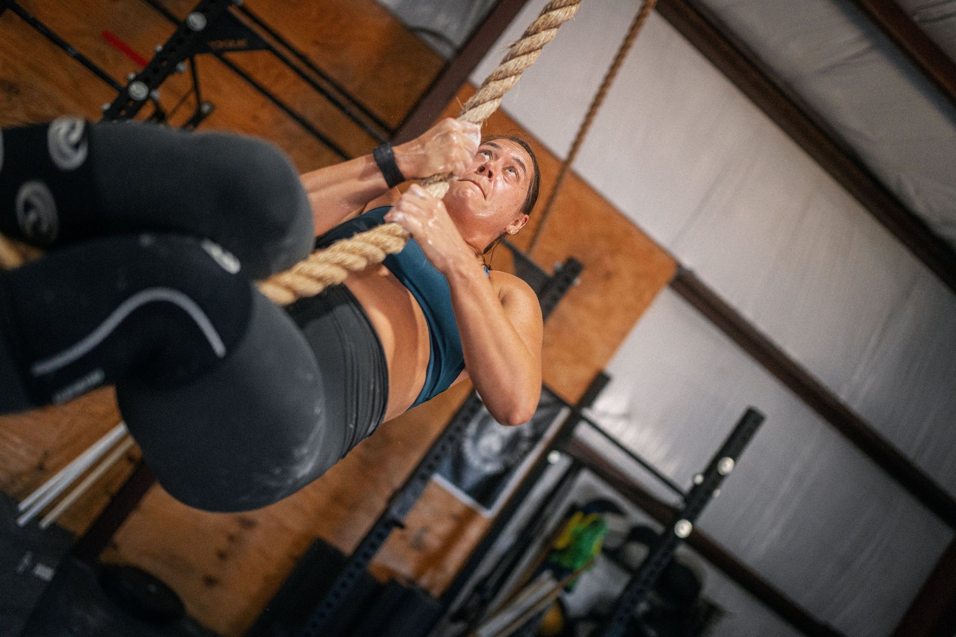 A woman is climbing a rope in a gym.