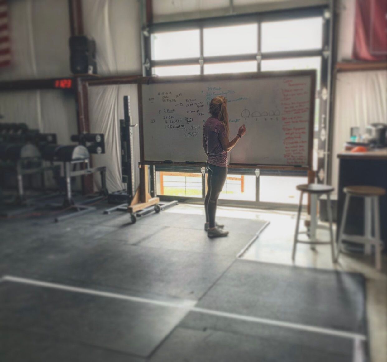 A woman is standing in front of a white board with numbers on it